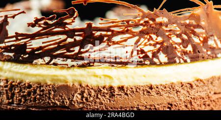 Creamy and delicate three-layered mousse cake with dark, milk, and white chocolate, a chocolate biscuit base, and abstract decoration. Stock Photo