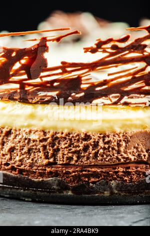 Creamy and delicate three-layered mousse cake with dark, milk, and white chocolate, a chocolate biscuit base, and abstract decoration. Stock Photo