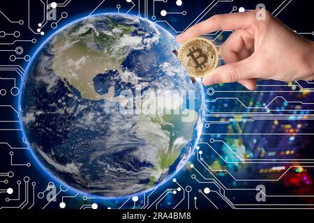 World cryptocurrency. Man inserting bitcoin into globe against digital scheme and blurred cityscape Stock Photo