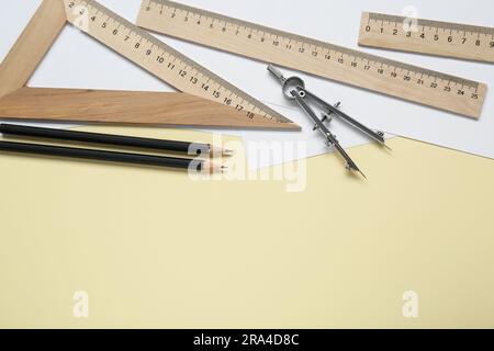 Different rulers, pencils and compass on yellow background, flat lay. Space for text Stock Photo