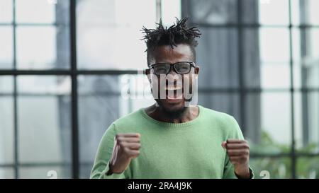 oyful bearded man in formal clothes, clenching his fists with happiness Stock Photo