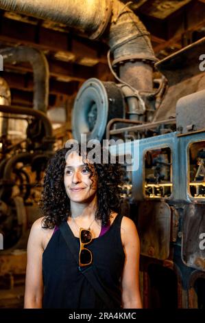Portrait of a mixed race woman smiling while posing inside an abandoned factory. Stock Photo