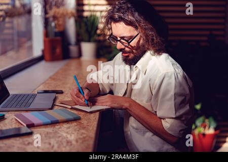 Young businessman making notes during working day at coworking space near window Stock Photo