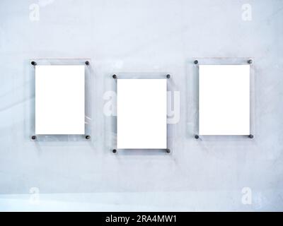 Three mockups of white blank paper poster or photo frames, acrylic materials, vertical style hanging on white dirty wall background. Stock Photo