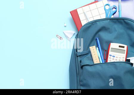 School backpack with different stationery on blue background Stock Photo