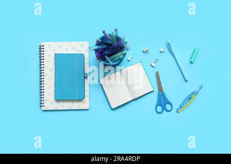Composition with notebooks and different school stationery on blue background Stock Photo