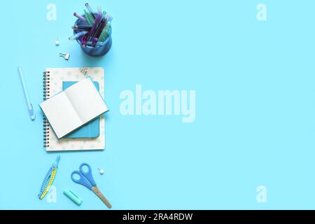 Composition with notebooks and different school stationery on blue background Stock Photo