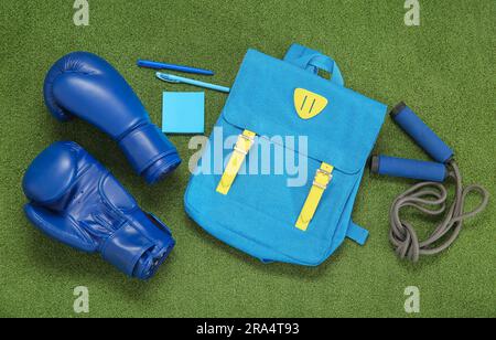 Backpack with boxing gloves, skipping rope and stationery on color background Stock Photo