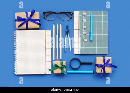 Gift boxes with magnifier, eyeglasses and different stationery on blue background Stock Photo
