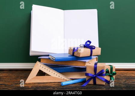 Gift boxes with books and different stationery on brown wooden table in classroom Stock Photo