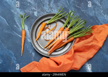 Plate of fresh carrots on blue textured background Stock Photo