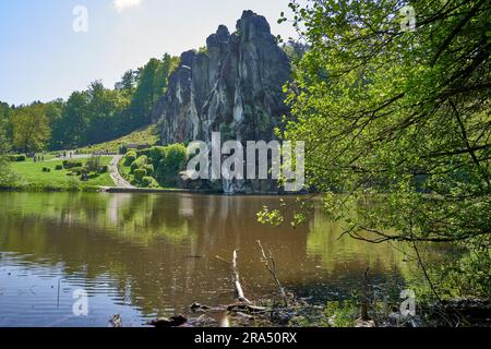 View across a sunny pond to the gigantic Externsteine in the Teutoburg Forest in Germany Stock Photo