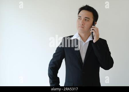 Young Asian businessman calling someone on the smartphone. Isolated white background. Stock Photo