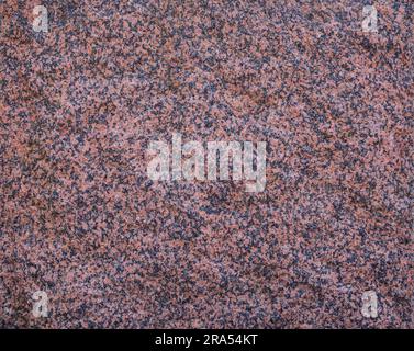 Close-up of natural red granite rock surface texture, front view. Abstract full frame textured background. Copy space. Stock Photo