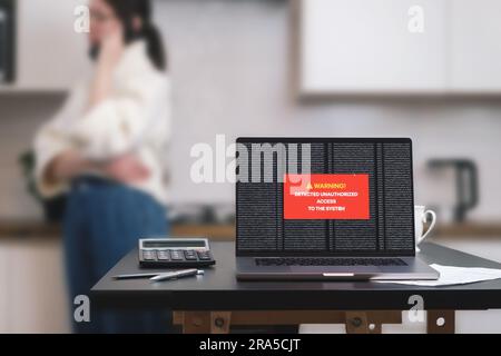 a laptop computer standing on a table with a system hacking message on the screen. Stock Photo