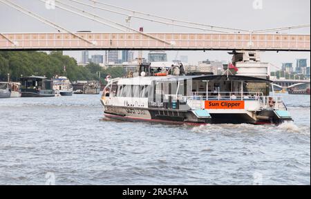 Closeup of a Thames Clipper Uber Boat passing under Rowland Mason Ordish's Albert Bridge in Chelsea, London, England, U.K. Stock Photo