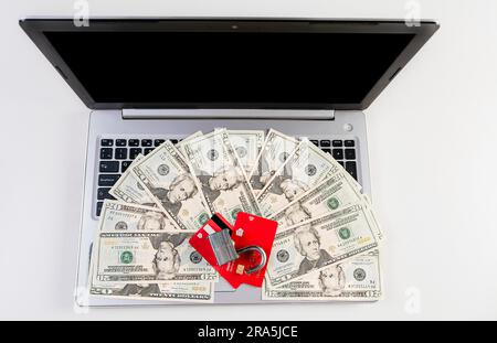 Top view of padlock with credit card on top of dollars on laptop keyboard. Padlock on top of credit card over dollar bills on computer keyboard Stock Photo