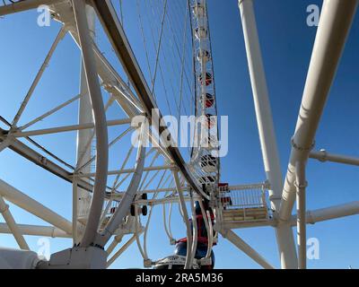 Big white ferris wheel against the blue sky. Part of the attraction on a blue background with copy space. Cabins, viewing. Stock Photo