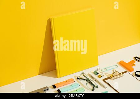 Back to school concept. Yellow blank hardcover book mockup, template on yellow and white background. Stationary flat lay, knolling Stock Photo