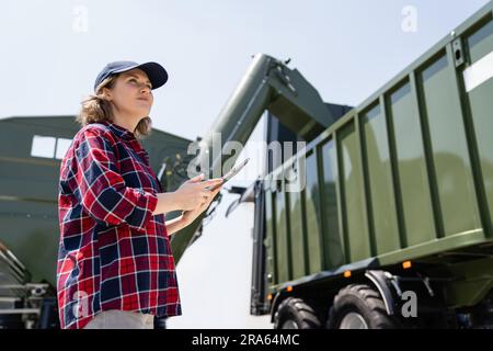 Woman farmer with tablet watching grain loading Stock Photo