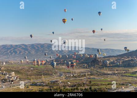 A picture of colorful hot air balloons flying over the landscape of Goreme Historical National Park at sunrise. Stock Photo