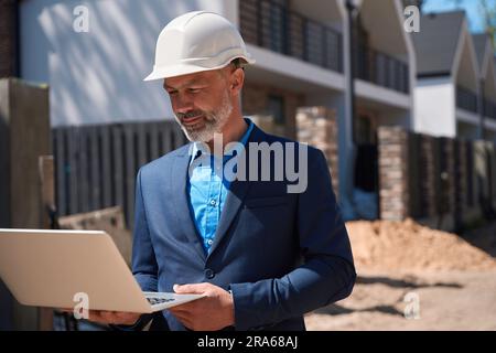Geodesist in business suit and hardhat inspecting construction site Stock Photo