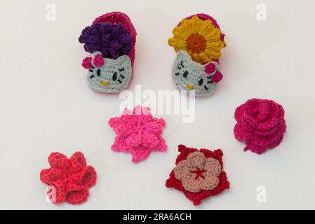 shoes with faces for a newborn and multi-colored flowers, crocheted, on a white background Stock Photo