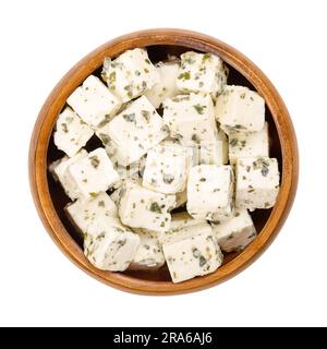 Greek feta cubes, brined cheese with Mediterranean herbs, in wooden bowl. Cheese, matured in brine, with soft and moist texture, fresh and salty taste. Stock Photo