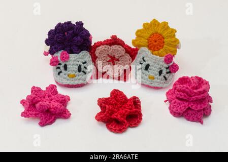 shoes with faces for a newborn and multi-colored flowers, crocheted, on a white background Stock Photo