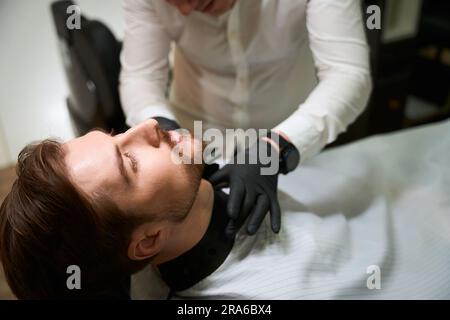 Male shaves stubble on the clients neck with special trimmer Stock Photo