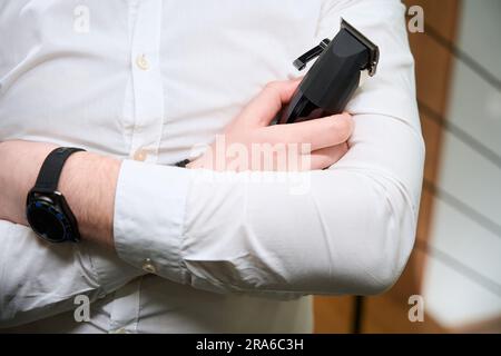 Man in a light shirt holds clipper in his hands Stock Photo