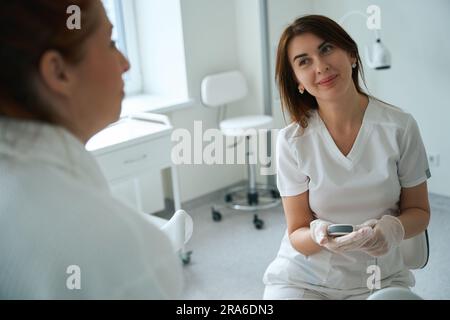 Gynecologist holding ultrasound probe near patient in clinic Stock Photo