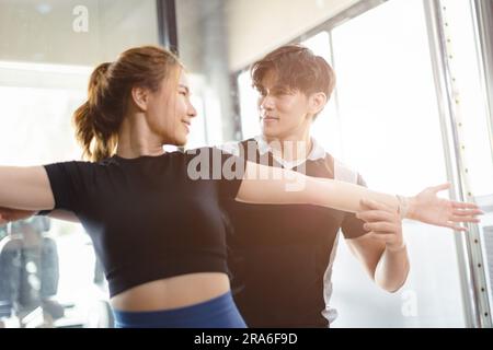 Healthy people asian young woman sport exercise in fitness gym sport club with personal trainer instructors help support. Stock Photo