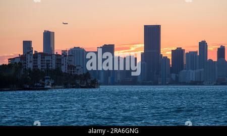 Miami Beach, Florida, USA. View from South Pointe Park, South Beach, across Biscayne Bay to Downtown Miami, sunset, plane approaching Miami Airport. Stock Photo