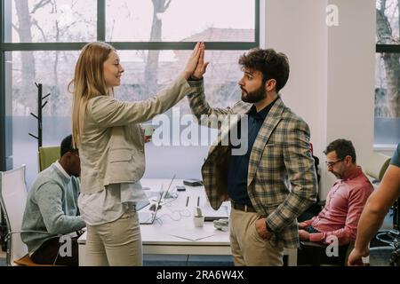 Two office colleagues doing a high five after agreeing on something at the office Stock Photo