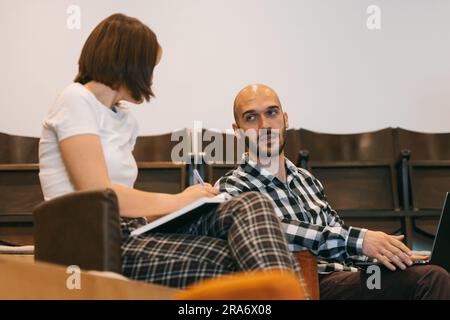 Good looking male employee explaining something to his female colleague during presentation at work Stock Photo