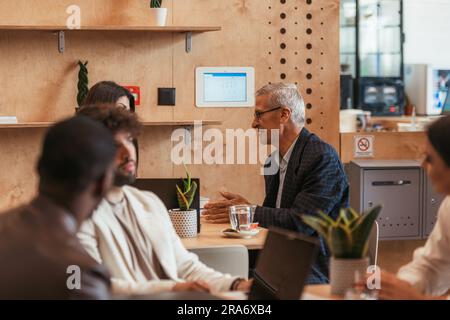 Senior businessman explaining something to his young colleague at the cafe Stock Photo