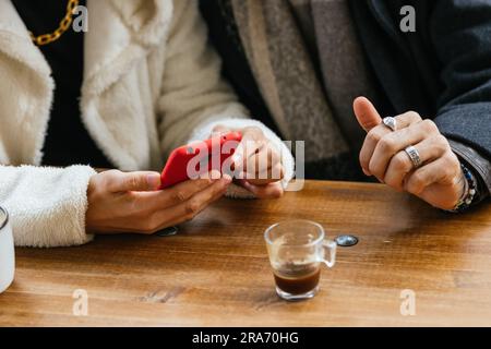: Gay Couple's Hands on Cafe Table with Smartphone Stock Photo