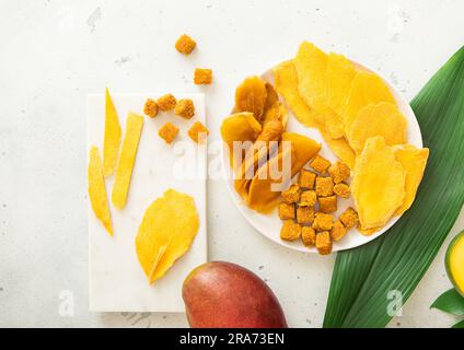 Dried mango pieces and balls in marble plates on light board with fresh fruits.Top view. Stock Photo