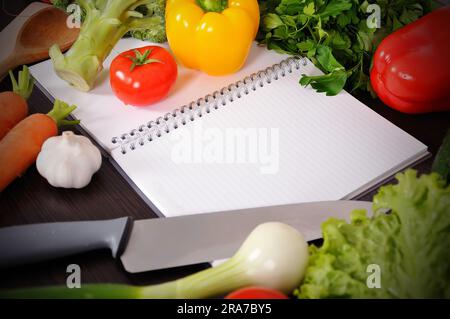 recipe book with vegetables on wooden table Stock Photo