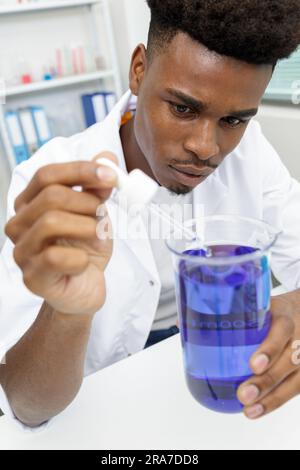 young man scientist using auto-pipette with flask in medical laboratory Stock Photo