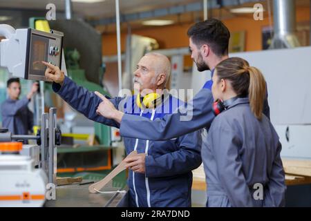 engineer and apprentice using automated machinery Stock Photo
