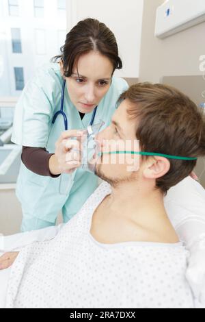 nurse install oxygen mask on patient in hospital room Stock Photo