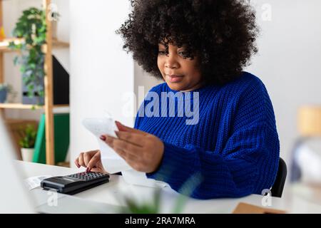 Young latina woman checking financial bills sitting on table at home Stock Photo