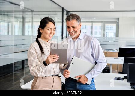 Two happy professional business people workers using digital tablet in office. Stock Photo