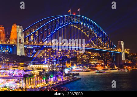 Arch of Sydney Harbour bridge with bright illumination over harbour waters at Vivid Sydney in Australia at night. Stock Photo