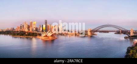 Close sunrise lit cityscape of City of Sydney harbour waterfront architecture landmarks in aerial panorama. Stock Photo