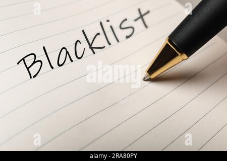 Writing word Blacklist with pen in notepad, closeup Stock Photo
