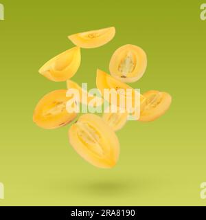 Cut fresh ripe pepino melons falling on yellow green background Stock Photo
