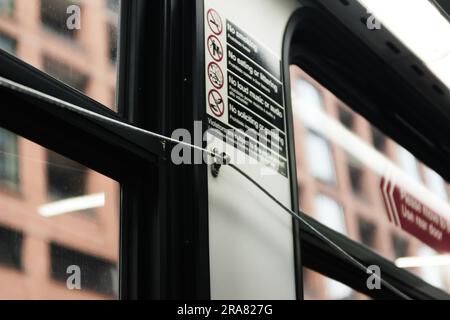 Close-up of bus passenger pull cord to request stop, brick buildings seen through the adjacent windows. Stock Photo